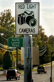 许多警察摄像头安装在交通交叉路口中，以捕捉运行红灯的人。“border=