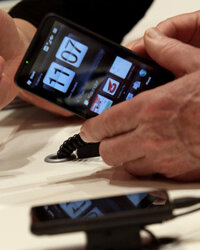 一位访客在2010年3月3日在德国汉诺威的CEBIT技术展览会上审查了沃达丰立场的HTC智能手机。乐动-软件”border=
