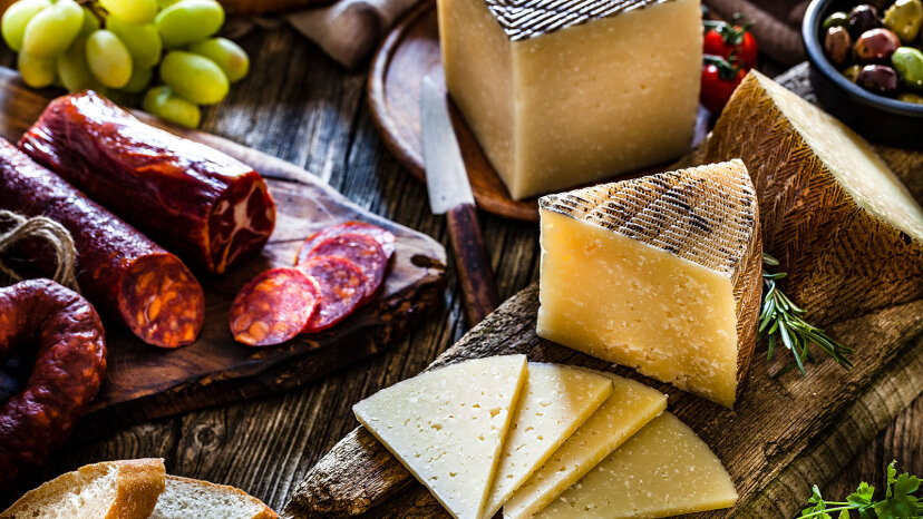 Pedazos de queso manchego rodeados de chorizo español, aceitunas, rebanadas de pan y uvas.