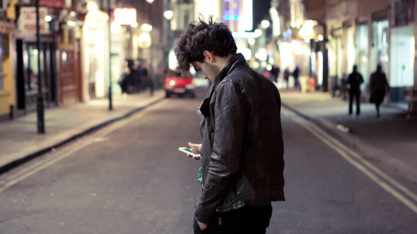 muž s telefonem na rušné ulici